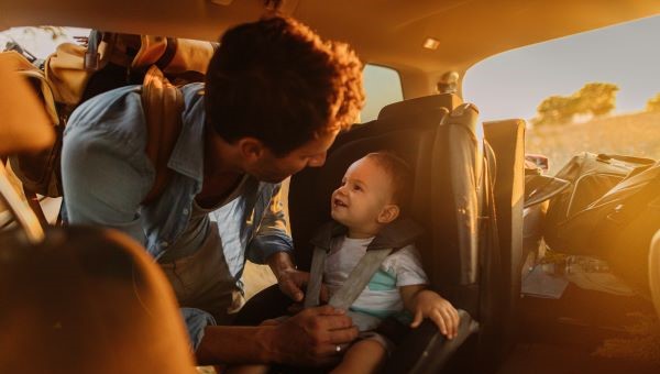Man putting baby into car seat in car