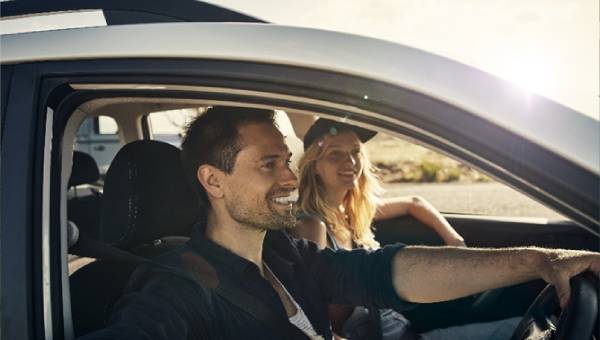 A man is driving with a female passenger.
