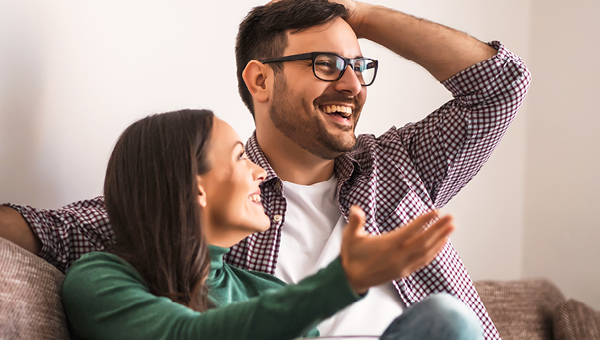 Smiling couple sitting together at home discussing their People’s Choice home loan options