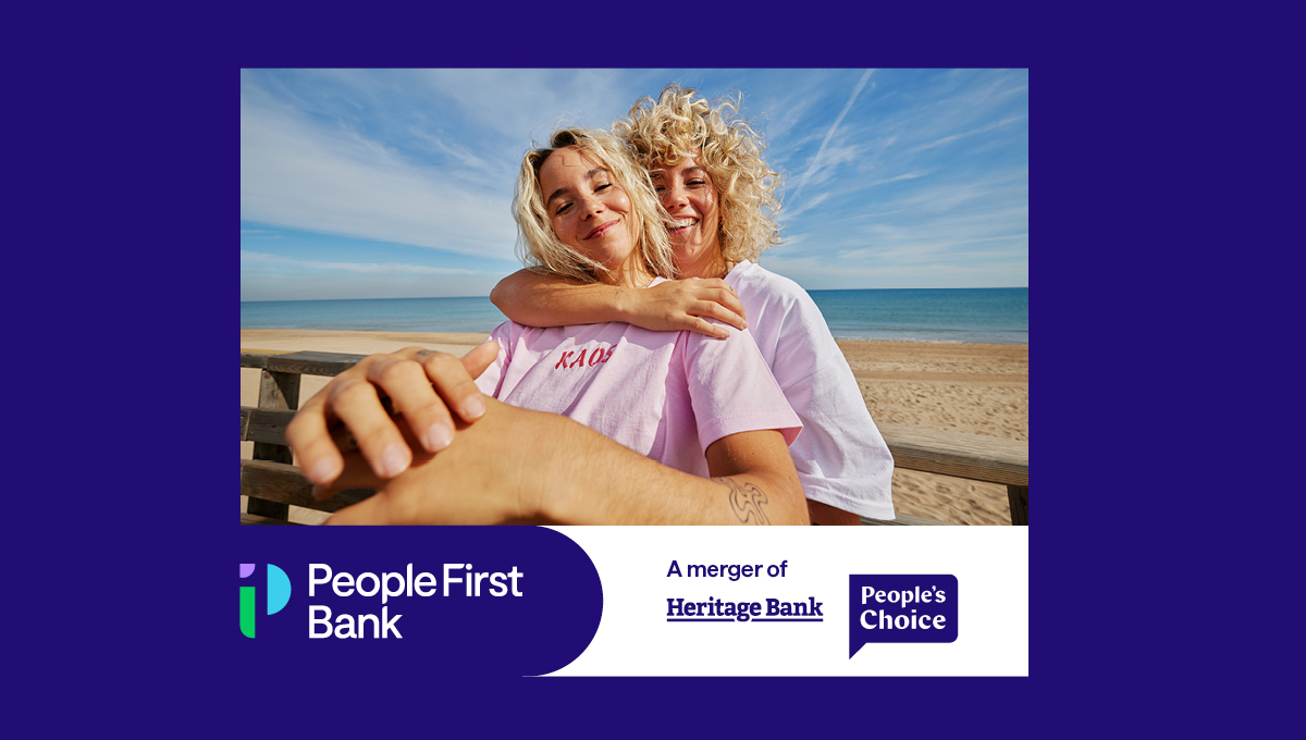 Two women cuddling at the beach. Underneath there is a bar with the new People First Bank logo on the left and the Heritage Bank and People's Choice logos on the right with text saying "A Merger of".