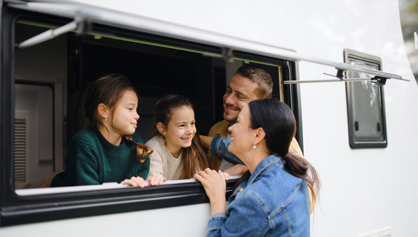 Children inside caravan interacting with adult through open window.